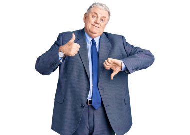 Kıdemli, gri saçlı, iş ceketi giyen, baş parmak kaldıran, anlaşmazlık ve anlaşma ifadesi takınan bir adam. çılgın çatışma 