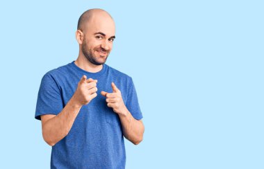 Sıradan tişörtler giyen genç yakışıklı adam mutlu ve komik yüzüyle kamerayı işaret ediyor. iyi enerji ve titreşimler. 