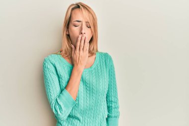 Kış süveteri giyen güzel sarışın kadın ağzıyla ağzını kapatmaktan sıkılmış. Huzursuz ve uykulu.. 