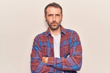 Gündelik kıyafetler giyen, kuşkucu ve gergin genç yakışıklı bir adam. Yüzünde çapraz kollarla onaylamayan bir ifade var. negatif kişi. 