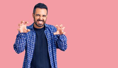 Gündelik kıyafetler giyen genç İspanyol adam komik gülüyor kedi gibi pençe hareketi yapıyor, agresif ve seksi bir ifade. 