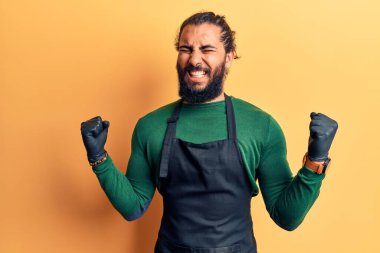 Berber önlüğü giymiş genç bir Arap. Çok mutlu ve heyecanlı. Kolları havada, gülümseyen ve başarı için bağıran kazanan bir jest yapıyor. kutlama konsepti. 