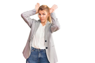 Zarif ceket giyen güzel sarışın kadın tavşan kulağı hareketi yapıyor avuçlarıyla alaycı ve şüpheci görünüyor. Paskalya tavşanı konsepti. 