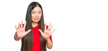 Günlük kıyafetler giyen genç Çinli kadın korku ifadesinden korkuyor ve dehşete düşüyor. El hareketlerini durdur, şok içinde bağır. panik konsepti. 