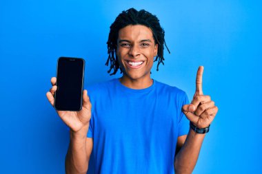 Genç Afrikalı Amerikalı bir adam elinde akıllı telefonuyla boş ekranda gülümsüyor bir fikir veya soru işareti ile mutlu bir yüzle, bir numara 