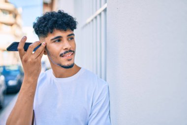 Genç Arap adam şehirdeki akıllı telefonu kullanarak sesli mesaj dinliyor.