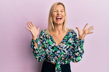 Orta yaşlı beyaz kadın, sıradan kıyafetler giyip başarıyı kutluyor. Kolları havada, gözleri kapalı, heyecanlı çığlıklar atıyorlar. Kazanan konsept 