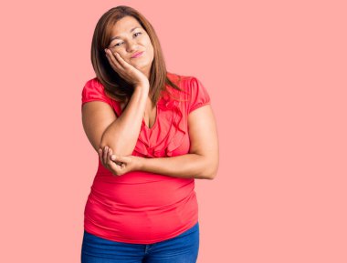 Güzel, orta yaşlı bir kadın günlük kıyafetler giyip kollarını kavuşturarak depresyondan sıkılmış ve yorgun görünüyor..