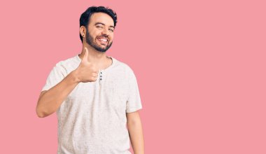 Gündelik kıyafetler giyen genç İspanyol adam elleriyle mutlu bir jest yapıyor. Kameraya bakıp başarıyı gösteren ifade. 