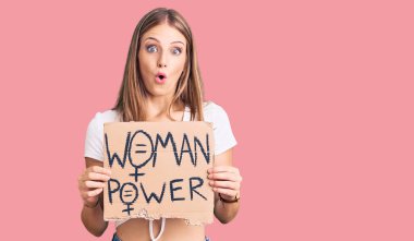 Sarışın, genç bir kadın elinde güç pankartı tutuyor. Korkmuş ve hayrete düşmüş bir şekilde ağzı açık, inançsız bir yüz. 