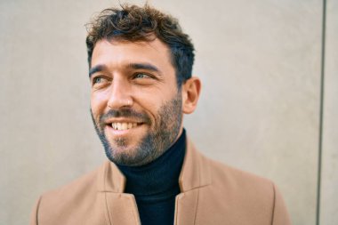 Zarif ceket giyen yakışıklı iş adamı dışarıda mutlu bir şekilde gülümsüyor.