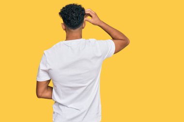 Genç Arap adam, günlük beyaz t-shirt 'ünü ters giyip elleri kafasında şüpheyi düşünüyor. 