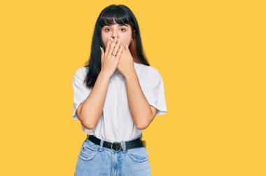 Gündelik kıyafetler giyen genç İspanyol kız yanlışlıkla elleri ile ağzını kapatırken şok oldu. gizli kavram. 