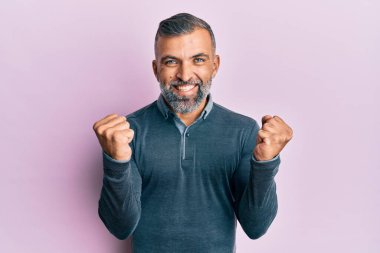 Orta yaşlı, sıradan kıyafetler giyen yakışıklı bir adam kollarını kaldırıp, gözlerini açarak başarının şaşkınlığını ve şaşkınlığını yaşıyor. Kazanan konsept. 