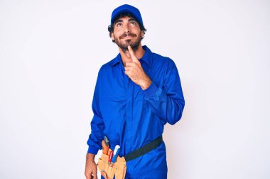 Kıvırcık saçlı ve ayı gibi giyinen yakışıklı bir genç adam. Düşünceleri kuşkuya odaklanmış, çenesi parmaklarla çevrili ve yukarı bakıyor. 