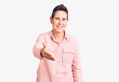 Kısa saçlı, günlük kıyafetler giyen, neşeli gülümseyen, yardım eli uzatan ve kabul gören genç bir kadın.. 