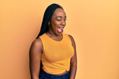 Genç Afro-Amerikan kadın, günlük giysiler içinde kameraya seksi bir ifadeyle bakıyor, neşeli ve mutlu bir yüzle.. 