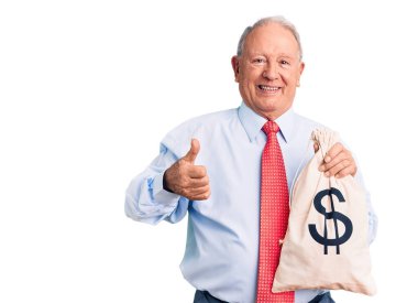 Kıdemli yakışıklı, gri saçlı, şık kıyafetler giyen, elinde para çantası tutan mutlu ve pozitif gülümseyen, başparmağıyla mükemmel ve onay işareti yapan bir adam. 