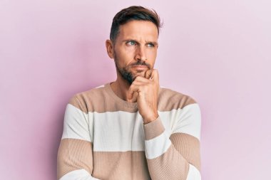 Sakallı, sıradan kıyafetler giyen yakışıklı. Kuşkuya odaklanmış, çenesinde parmak olan ve kafasını kaldırıp merak eden biri. 