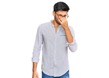 Gündelik kıyafetler ve gözlük takan genç yakışıklı adam yorgun burnu ve gözleri ovuşturup yorgun ve baş ağrısı çekiyor. Stres ve hüsran kavramı. 