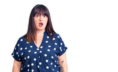 Genç ve cüsseli kadın gündelik kıyafetler giyiyor. Şaşırmış ve şaşırmış bir ifade, korku ve heyecanlı bir yüz ifadesi var.. 