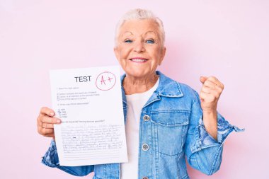 Senior beautiful woman with blue eyes and grey hair showing a passed exam screaming proud, celebrating victory and success very excited with raised arms 