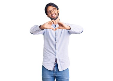 İş gömleği ve gözlük takan yakışıklı, aşık gülümseyen, elleriyle kalp sembolü yapan yakışıklı bir adam. romantik kavram. 