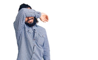 Genç Arap adam gündelik giysiler giyip kollarıyla gözlerini kapatıyor neşeli ve komik gülümsüyor. kör kavram. 