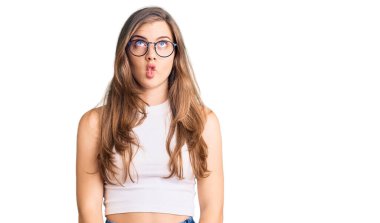 Gündelik kıyafetler ve gözlük takan güzel beyaz bir kadın dudaklarıyla balık suratı yapıyor, çılgınca ve komik bir jest. Komik ifade. 