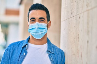 Tıbbi maske takan genç İspanyol adam şehirde dikiliyor..