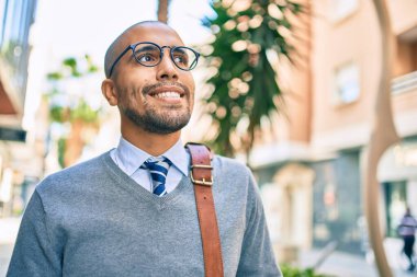 Genç Afrikalı Amerikalı iş adamı gülümseyerek şehirde mutlu bir şekilde yürüyor..