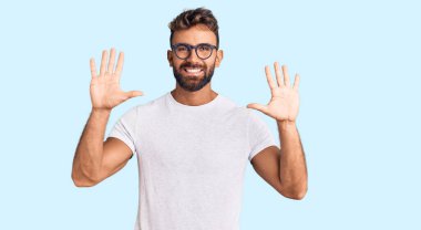 Gündelik kıyafetler giyen ve gözlük takan İspanyol genç adam on numarayı gösterip işaret ederken kendinden emin ve mutlu gülümsüyor.. 