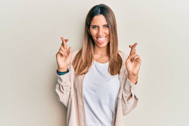 Esmer genç kadın parmaklarını çapraz yapıyor. Dilini çıkartıyor. Komik bir ifadeyle mutlu.. 