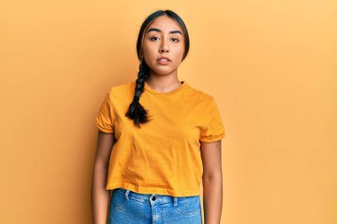 Gündelik kıyafetler giyen genç Latin kadın yüzünde ciddi bir ifadeyle rahatlamış. Basit ve doğal bir şekilde kameraya bakıyorsun.. 