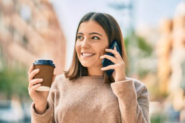 Genç İspanyol kadın akıllı telefonda konuşuyor. Şehirde kahve içiyor..