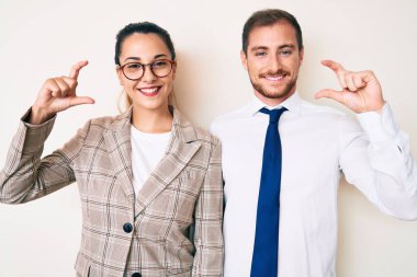 Güzel bir çift iş kıyafetleri giyip gülümsüyor ve el hareketleriyle el hareketleriyle hareket ediyor parmaklarıyla işaret yapıyor ve kameraya bakıyor. ölçüm kavramı. 
