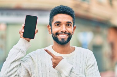Genç Afrikalı Amerikalı adam gülümsüyor. Şehre akıllı telefon gösterdiği için mutlu..