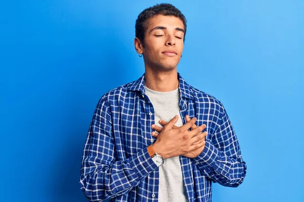 Sıradan kıyafetler giyen, göğsünde elleri, yüzünde minnet dolu bir jestle gülümseyen genç bir Afrikalı Amerikalı. sağlık kavramı. 