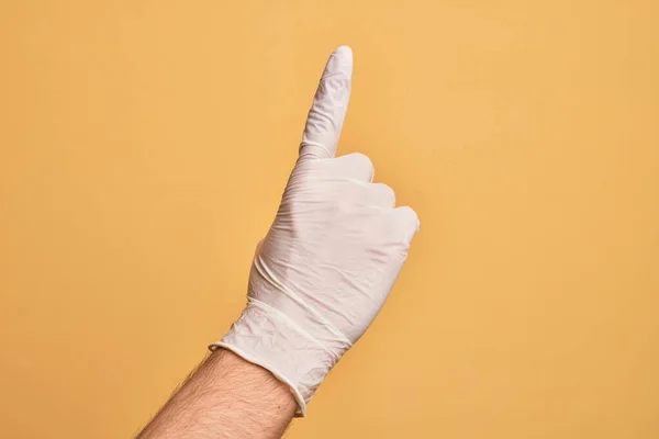 Mão Jovem Caucasiano Com Luva Médica Sobre Fundo Amarelo Isolado — Fotografia de Stock