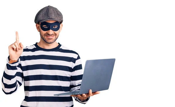 Young Handsome Man Wearing Burglar Mask Using Laptop Surprised Idea — Stock fotografie