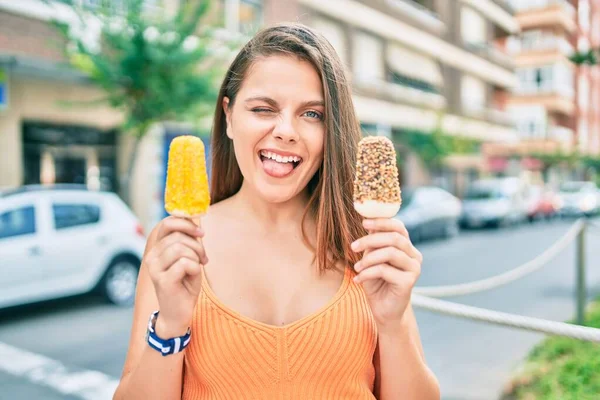 Genç ortadoğulu kız dil ısırıyor ve şehirde dondurma tutuyor..