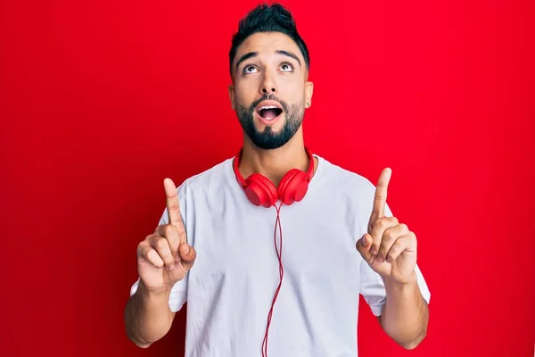 Sakallı Genç Adam Kulaklıkla Müzik Dinliyor Hayret Şaşkınlık Içinde Yukarı — Stok fotoğraf