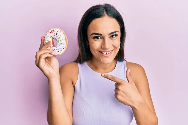 Joven Morena Sosteniendo Sabrosa Rosquilla Colorida Sonriendo Feliz Señalando Con — Foto de Stock