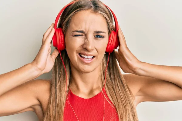 Jovem Loira Ouvindo Música Usando Fones Ouvido Piscando Olhando Para — Fotografia de Stock