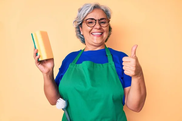 Ältere Hispanische Grauhaarige Frau Trägt Schürze Hält Scheuer Lächeln Glücklich — Stockfoto