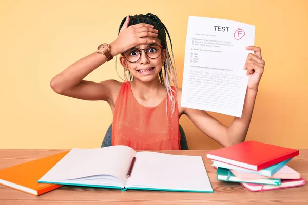 Young african american girl child with braids showing failed exam stressed and frustrated with hand on head, surprised and angry face