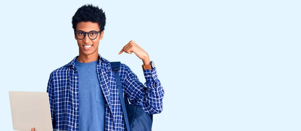 若いですアフリカ系アメリカ人男性保持学生バックパック使用ノートパソコン指差す指へ一人の自己笑顔幸せと誇り — ストック写真