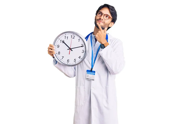 Hombre Hispano Guapo Vistiendo Uniforme Médico Sosteniendo Reloj Cara Seria — Foto de Stock