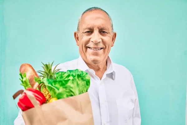 Hombre Mayor Sonriendo Feliz Sosteniendo Bolsa Papel Con Comida Caminando —  Fotos de Stock