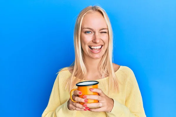 Menina Loira Jovem Segurando Café Piscando Olhando Para Câmera Com — Fotografia de Stock